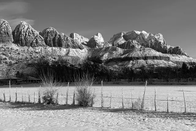 Snow-dusted rock towers above a snowy field, in black and white
