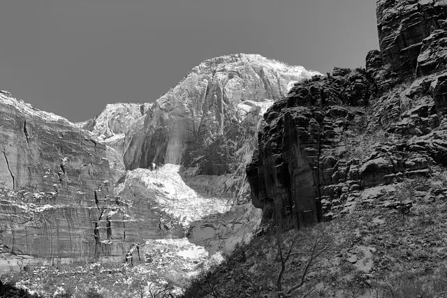 Layered cliff faces rising above snowy ground, in black and white