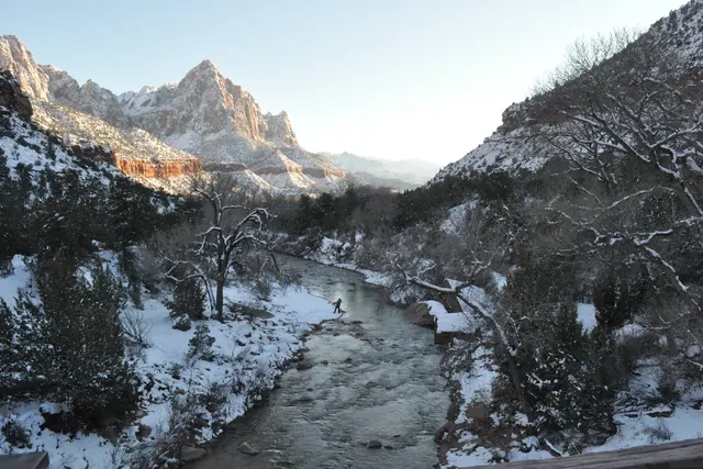 A river winding through snowy banks below a jagged red and white peak