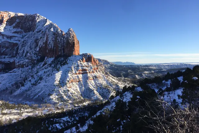 Snow-covered ridges and red cliffs above a wide valley in winter