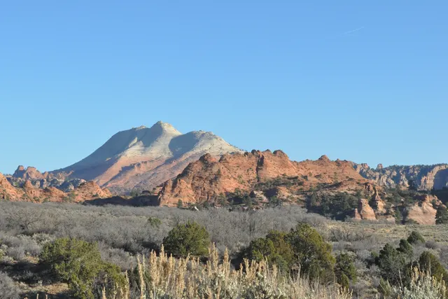 A pale, rounded peak rising above a sage-covered plain