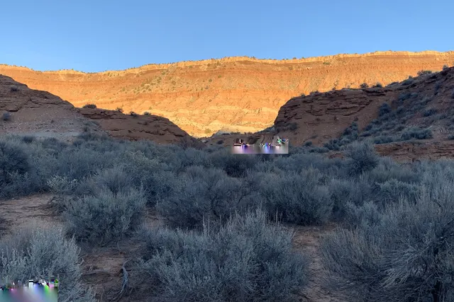 Red rock rim lit gold above a field of gray-green sage in low sunlight