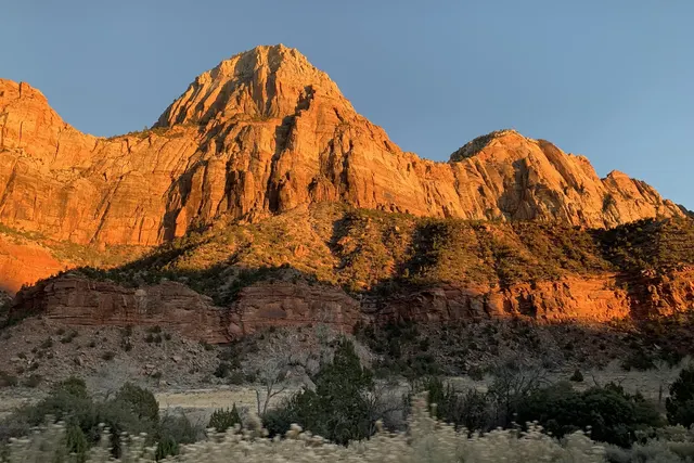 A sandstone peak glowing orange in low light against a pale sky