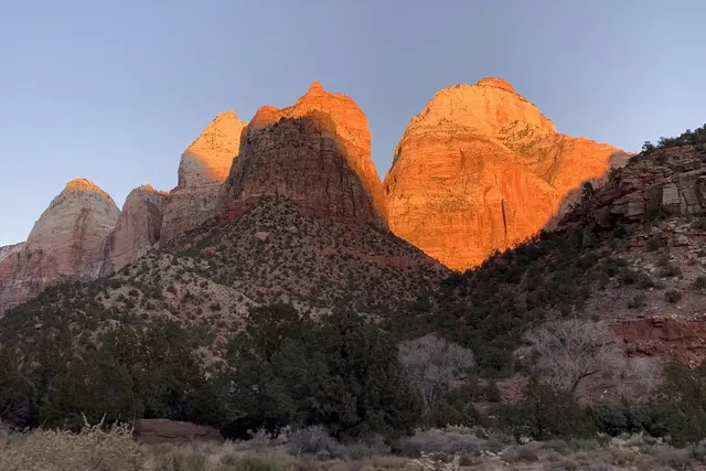 Twin sandstone summits glowing orange in low light against a blue-gray sky
