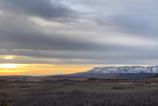 Gray clouds over a wide valley with a thin orange band of light