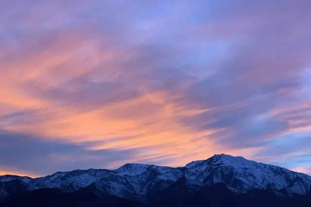 Pink and lavender sunset clouds over snow-capped peaks